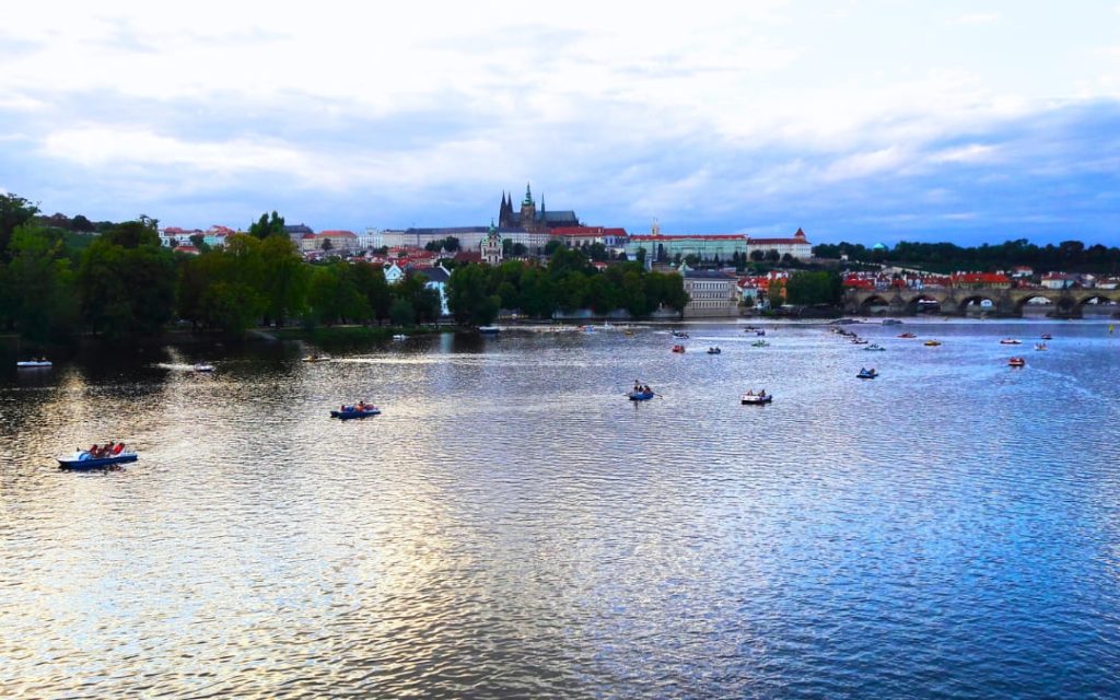 Łódki na wodzie a w tle panorama Pragi