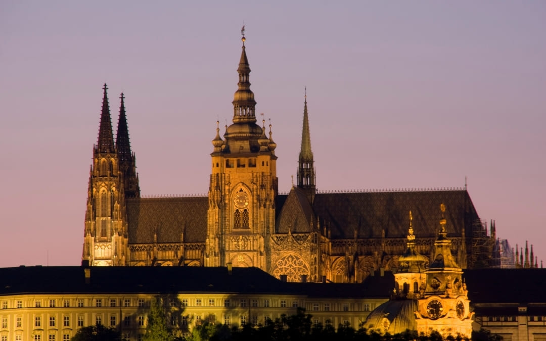 Nocna panorama Zamku Praskiego i Katedry św. Wita podświetlonych na fioletowym niebie