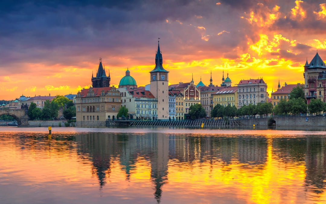 Panorama Pragi odbita w Wełtawie o zachodzie słońca z wieżami i kopułami Starego Miasta