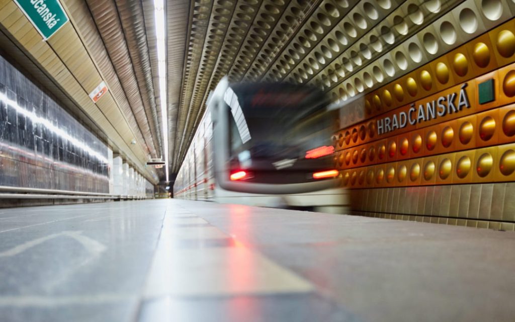 Pociąg metra wjeżdżający na stację Hradčanská w Pradze z charakterystyczną złoto-brązową ścianą