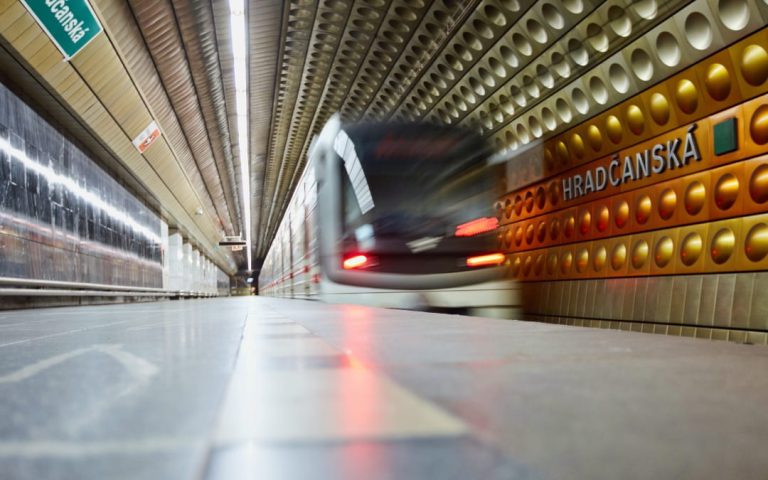 Pociąg metra wjeżdżający na stację Hradčanská w Pradze z charakterystyczną złoto-brązową ścianą