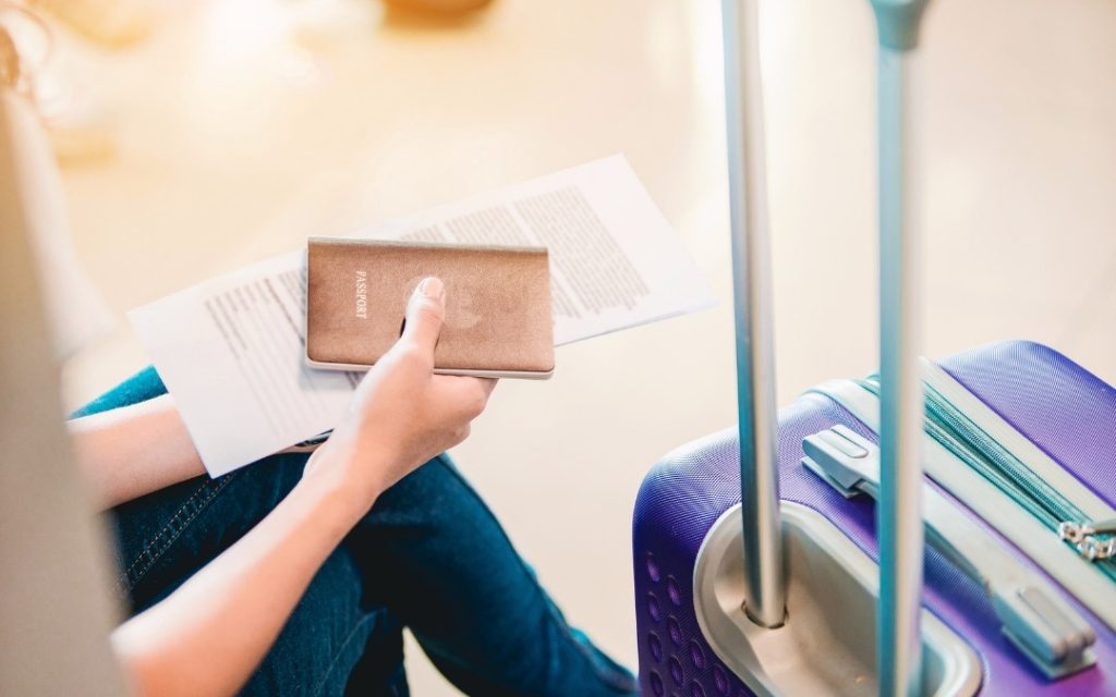 Podróżny przygotowany do lotu, trzymający paszport i kartę pokładową przy walizce