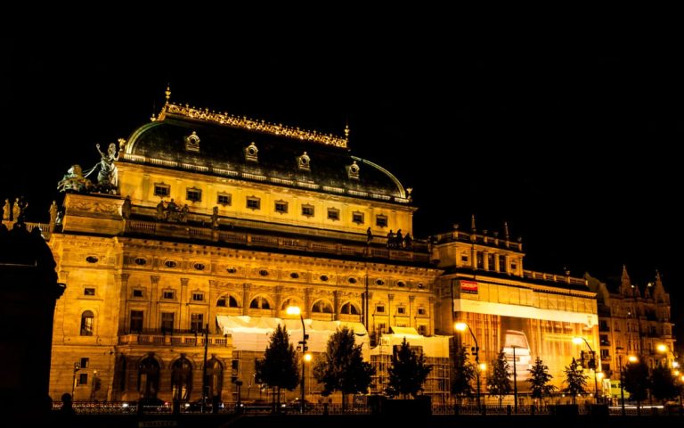 Teatr Narodowy w Pradze nocą podświetlony złotym światłem z widoczną kopułą