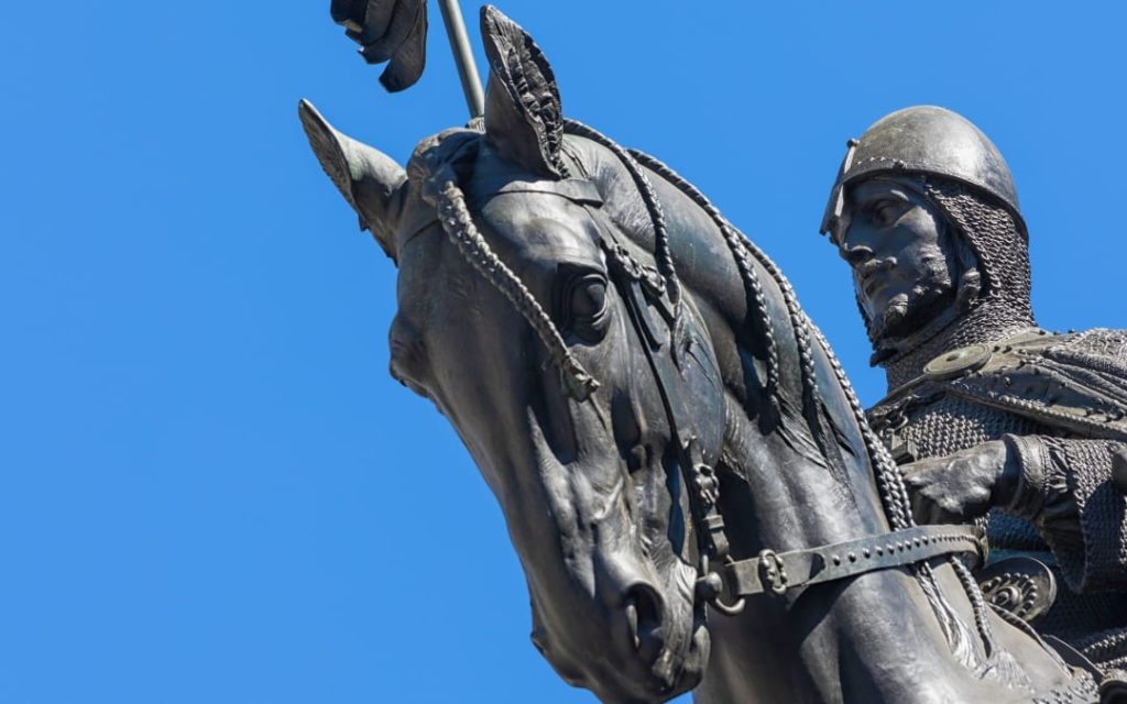 Zbliżenie na brązową głowę konia i rycerza z pomnika św. Wacława w Pradze na tle błękitnego nieba
