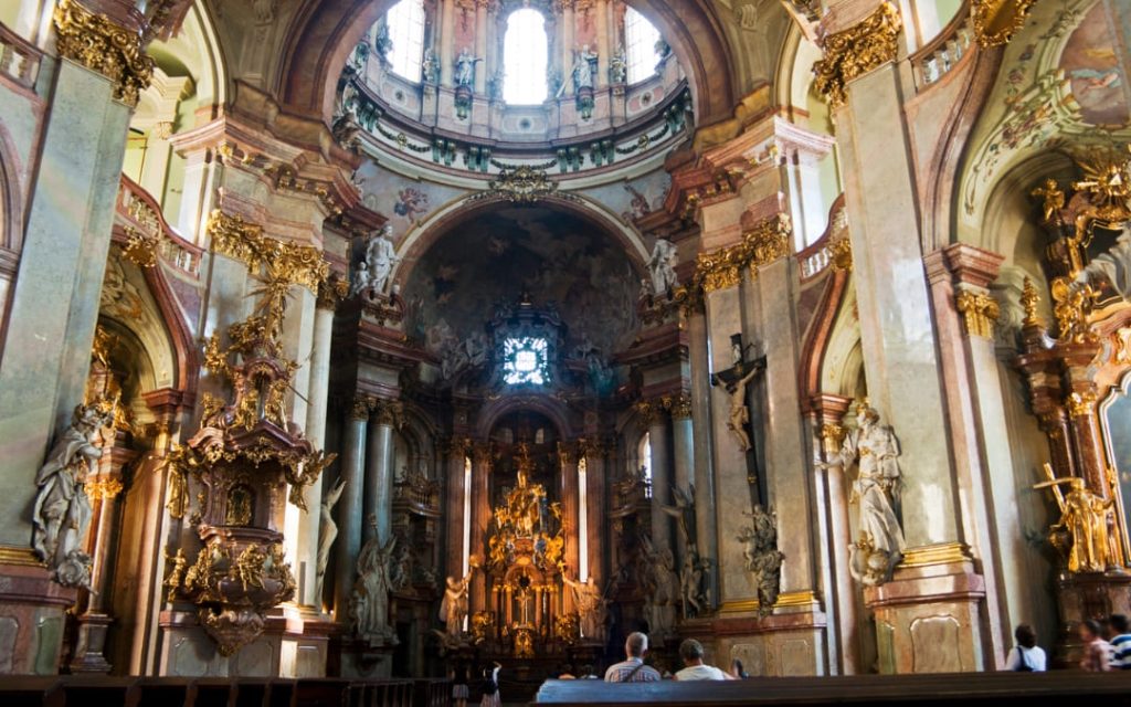 Złocone barokowe wnętrze Kościoła św. Mikołaja w Pradze z ołtarzem i rzeźbami