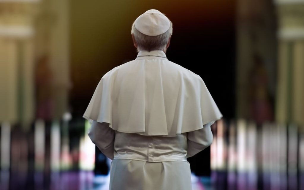 Papież odwrócony plecami idący w głąb ciemnego korytarza