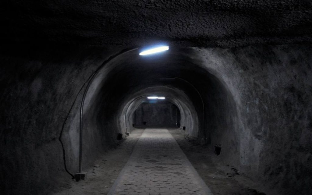 Oświetlony tunel z betonowym sklepieniem – przejście prowadzące w głąb podziemnego kompleksu