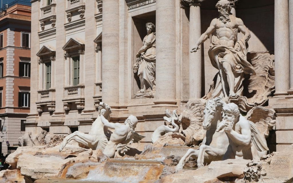 Barokowa Fontanna di Trevi w Rzymie z rzeźbami Neptuna, trytonów i koni morskich w pełnym słońcu