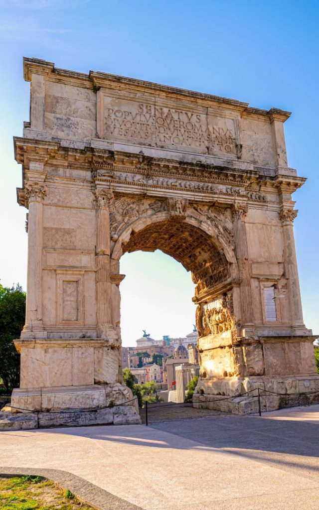 Biały marmurowy Łuk Tytusa na Forum Romanum z widoczną inskrypcją dedykacyjną i reliefami