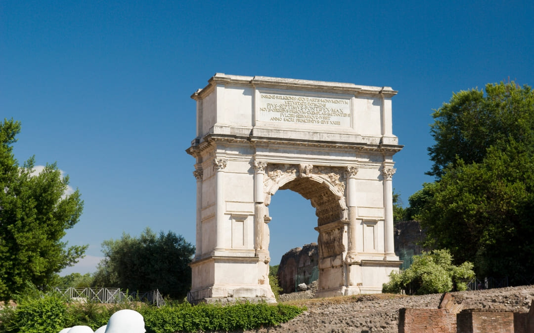 Biały, marmurowy Łuk Tytusa na Forum Romanum z widoczną łacińską inskrypcją na górze