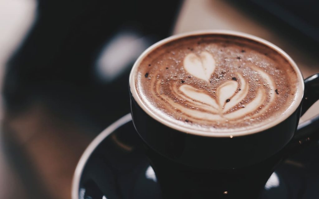 Czarna filiżanka kawy z latte art w kształcie tulipana w praskiej kawiarni