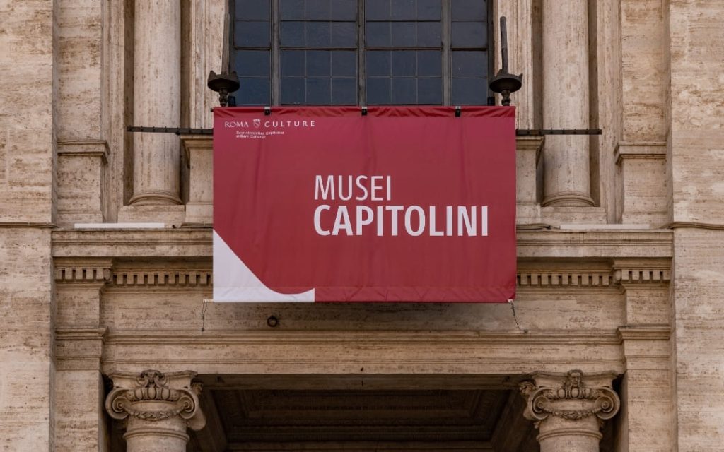 Czerwony baner z napisem Musei Capitolini nad wejściem do Muzeów Kapitolińskich w Rzymie