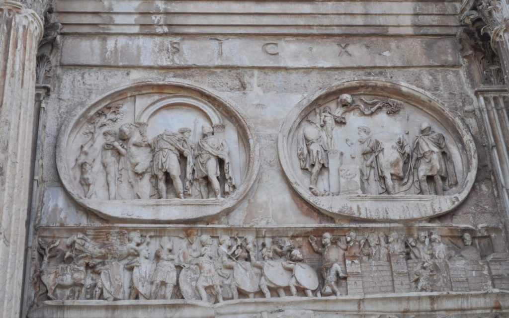 Dwa antyczne, okrągłe medaliony ze scenami polowań nad prostokątnym fryzem przedstawiającym rzymskie wojska pod murami miasta