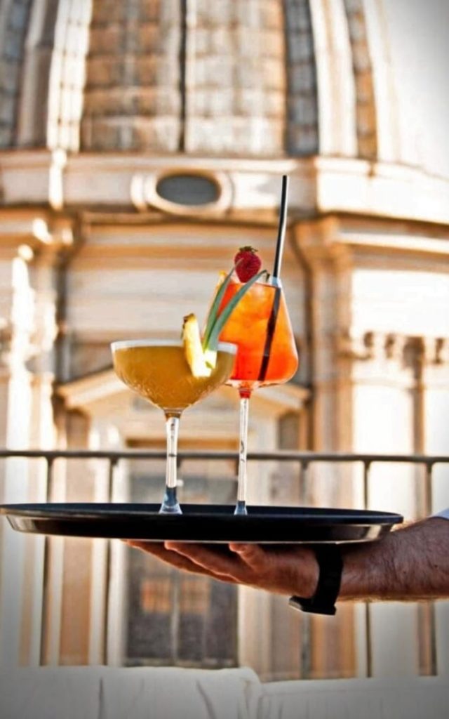 Eleganckie drinki na tacy w rzymskiej restauracji Terrazza Borromini na tle zabytkowej architektury
