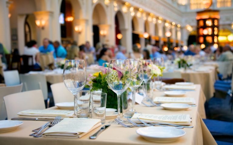 Elegancko nakryty stół w rzymskiej restauracji z białymi obrusami i kwiatami