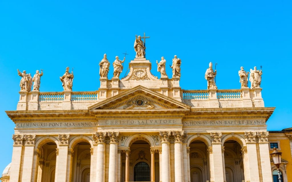 Fasada Bazyliki św. Jana na Lateranie z monumentalnymi rzeźbami świętych na tle błękitnego nieba