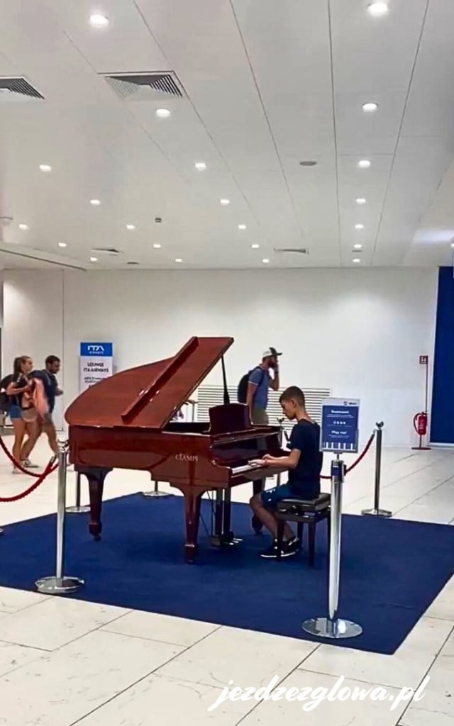Osoba grająca na fortepianie na lotnisku Fiumicino w Rzymie