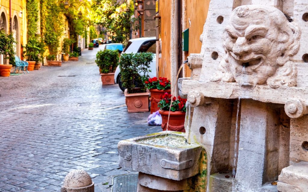 Historyczna fontanna Fontana delle Arti na Via Margutta w Rzymie z rzeźbionymi maskami i przyborami malarskimi