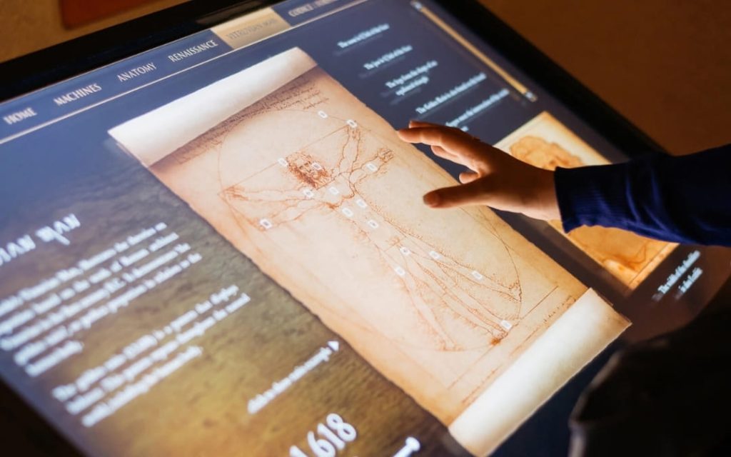 Interaktywny ekran dotykowy w Muzeum Leonarda da Vinci w Rzymie z opisem „Człowieka Witruwiańskiego”