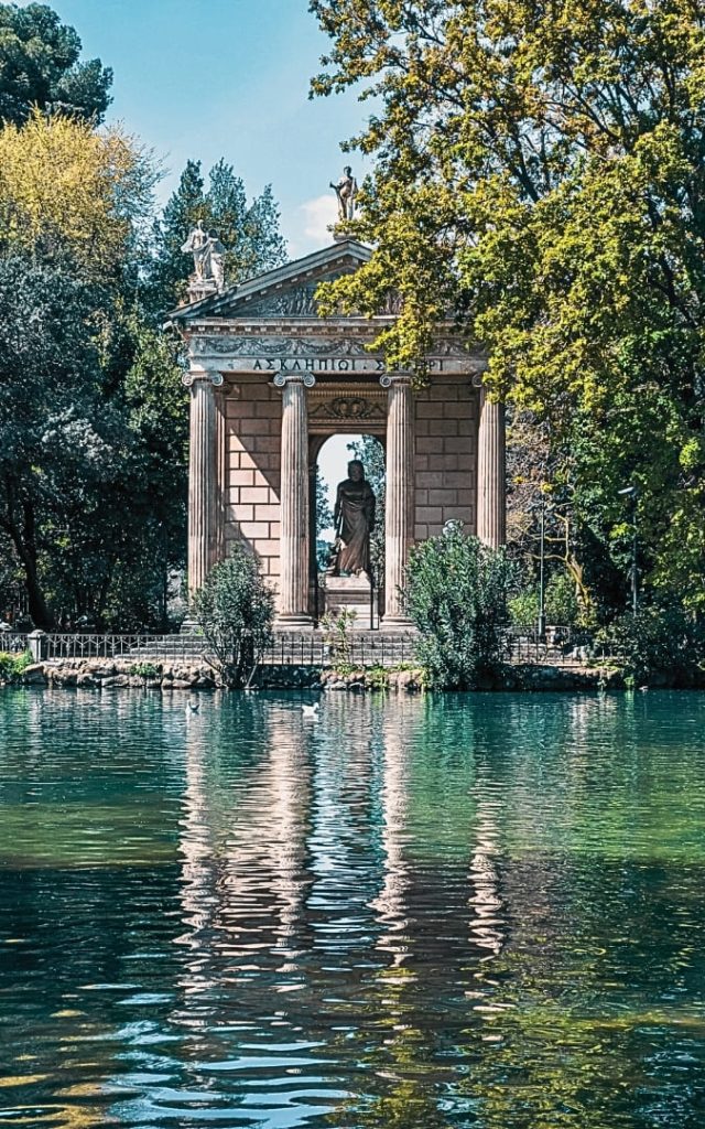 Klasyczna Świątynia Eskulapa w ogrodach Villa Borghese w Rzymie, odbijająca się w lustrze wody jeziora Giardino del Lago