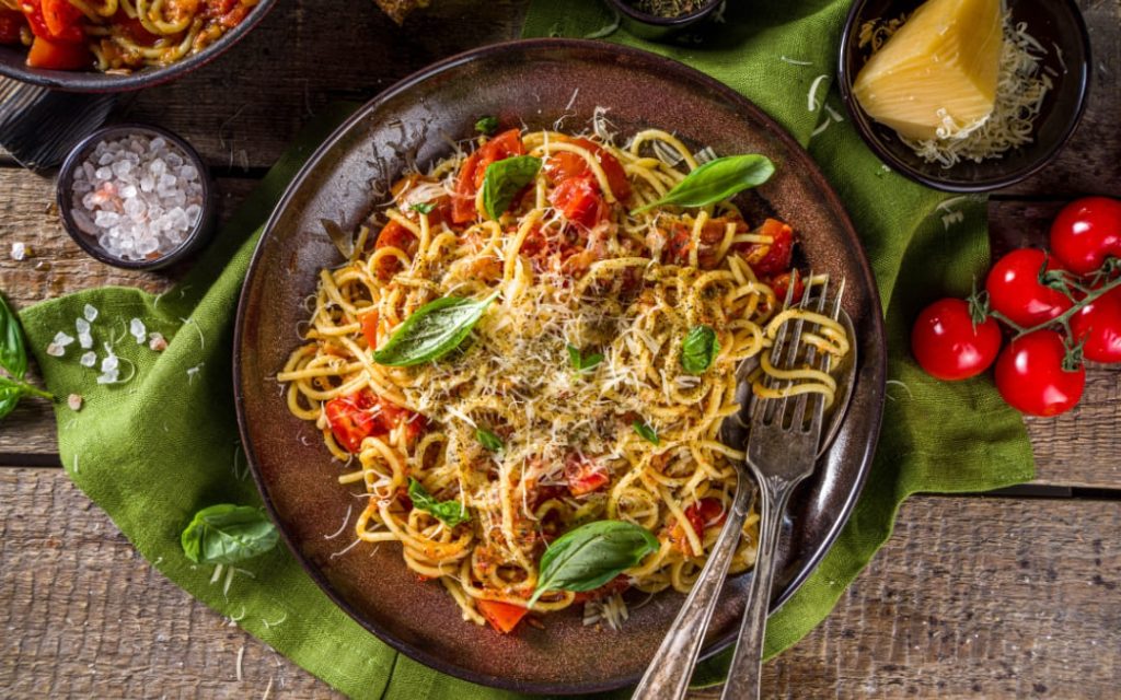 Klasyczna pasta amatriciana serwowana na talerzu z tartym serem i świeżymi ziołami