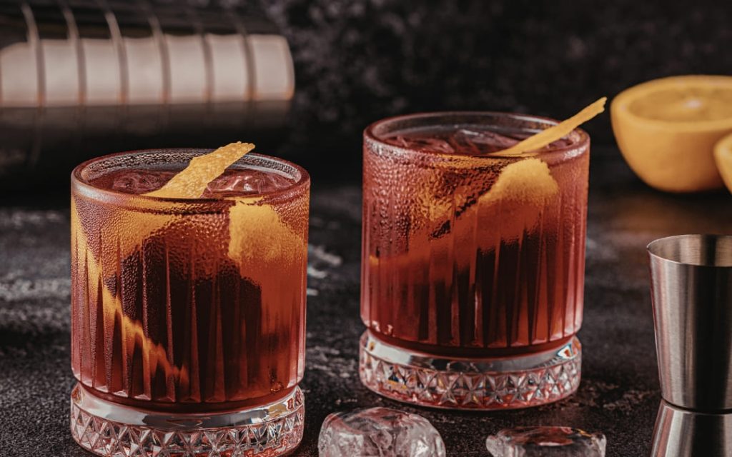 Klasyczny rzymski koktajl Negroni z lodem i skórką pomarańczy w kryształowych szklankach