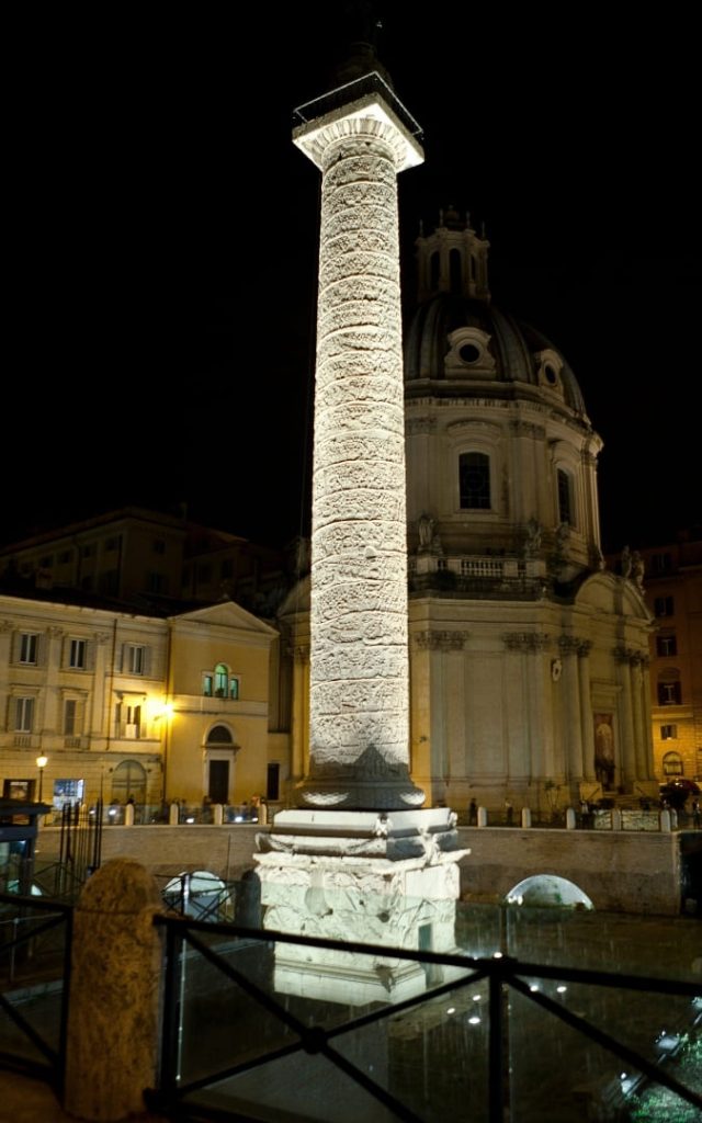 Kolumna Trajana w Rzymie nocą z widoczną kopułą kościoła Santissimo Nome di Maria