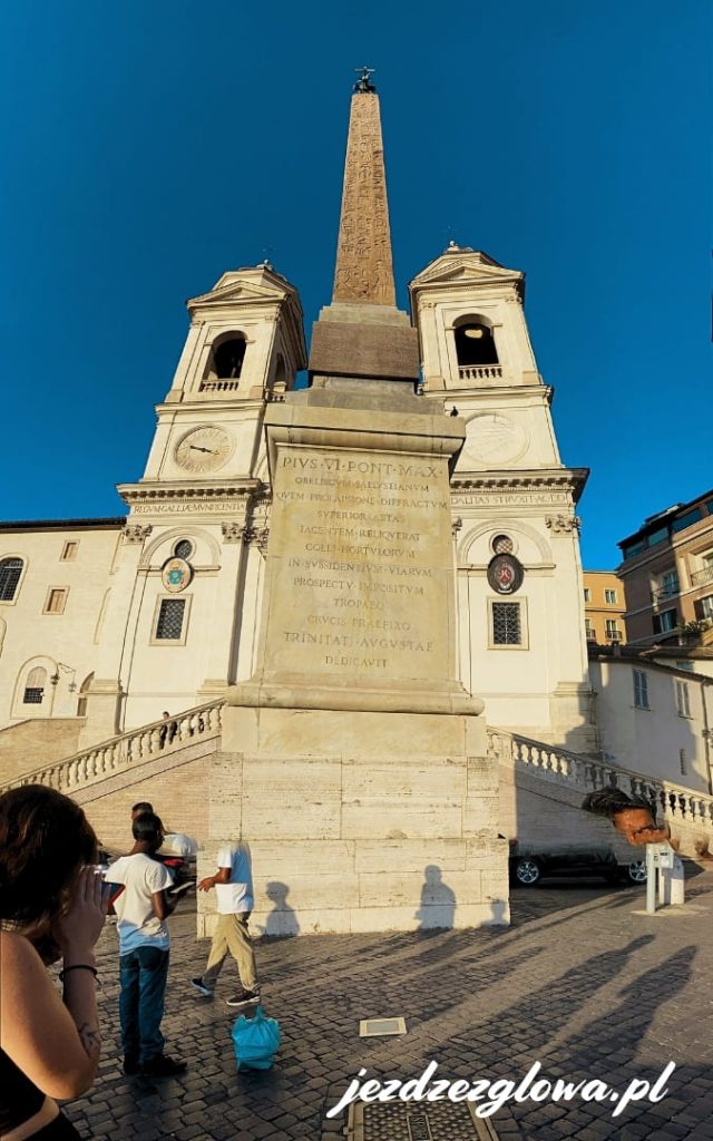 Obelisk Sallaustiano w Rzymie wraz z Kościołem Trinità dei Monti w tle w pogodny dzień