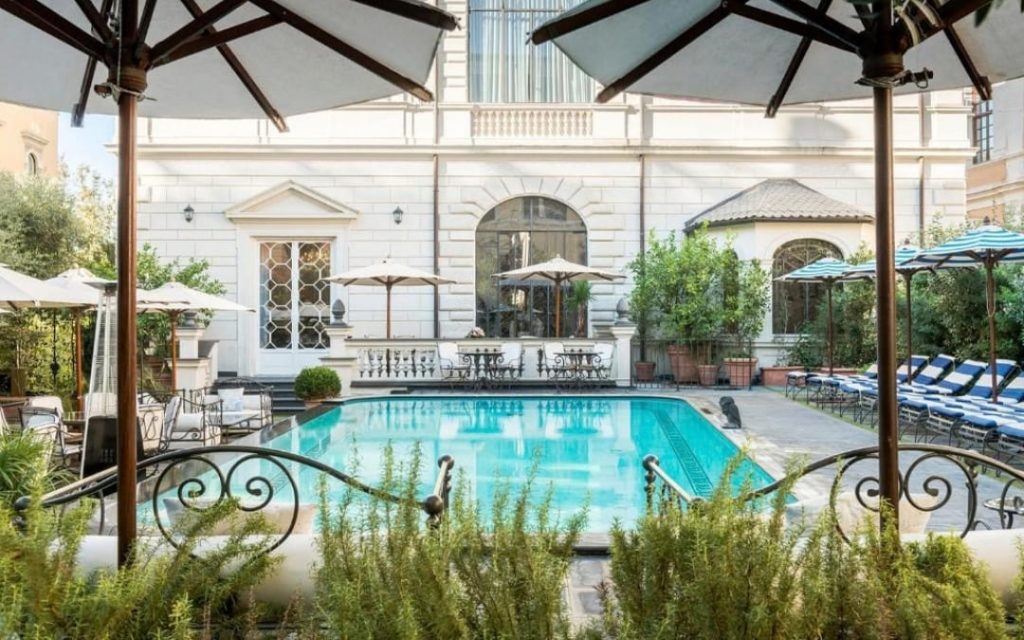 Luksusowy basen w rzymskim hotelu Palazzo Dama otoczony parasolami i leżakami