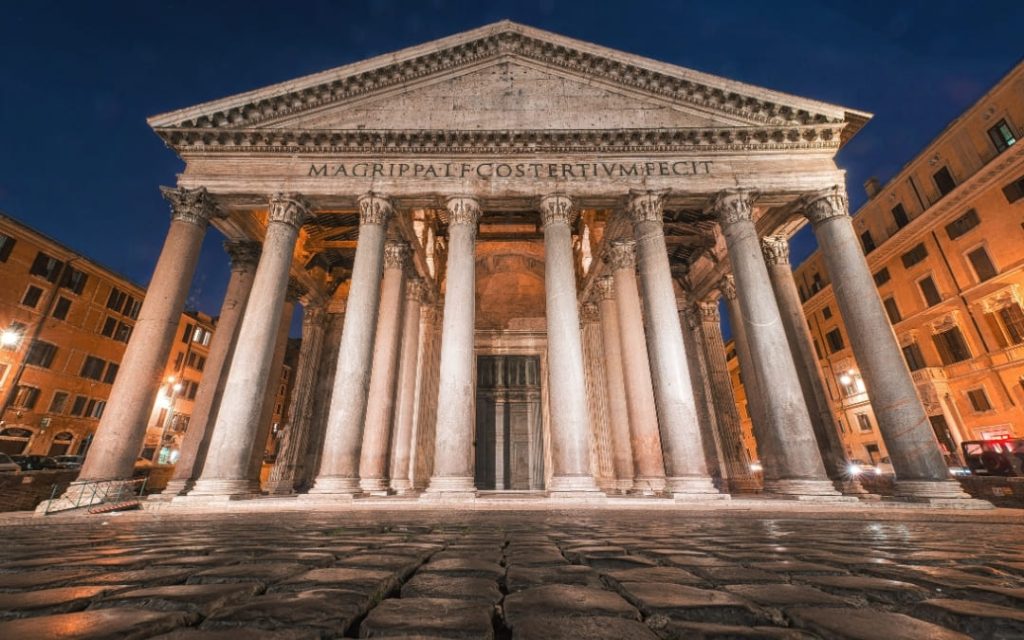 Oświetlona fasada antycznego Panteonu w Rzymie na tle nocnego nieba, widok z poziomu brukowanego placu
