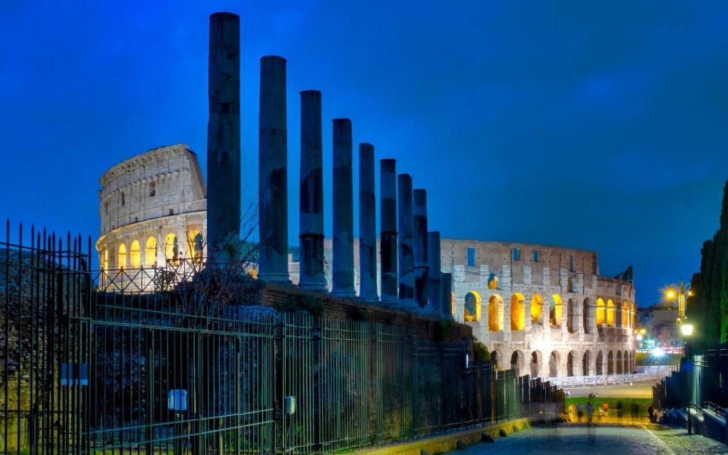 Oświetlone Koloseum i kolumny Świątyni Wenus i Romy przy Via Sacra w Rzymie po zmroku