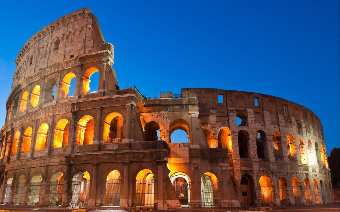 Oświetlone Koloseum w Rzymie wieczorem na tle nieba