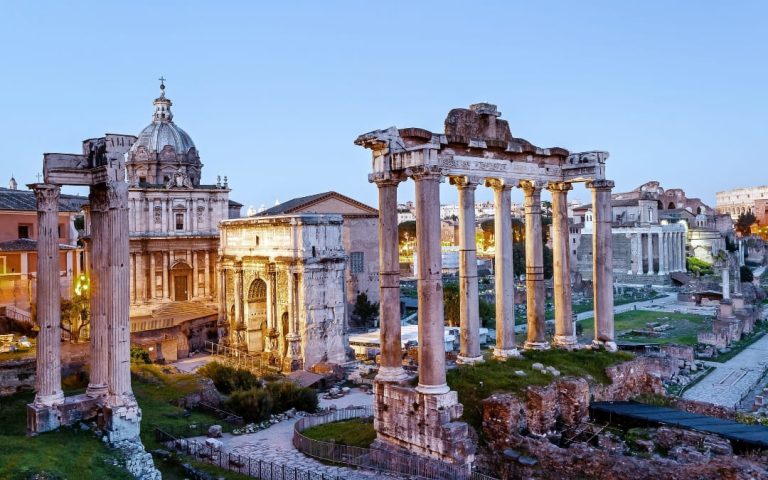 Oświetlone ruiny Forum Romanum z widoczną Świątynią Saturna i Łukiem Septymiusza Sewera wieczorem