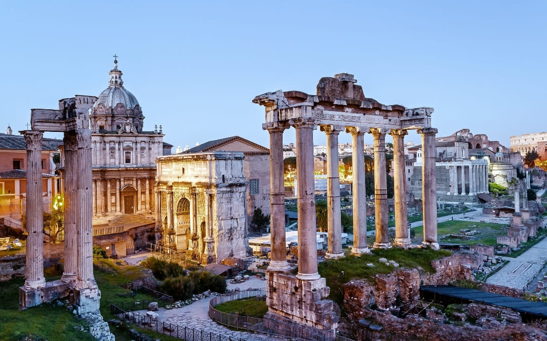Oświetlone ruiny Forum Romanum z widoczną Świątynią Saturna i Łukiem Septymiusza Sewera wieczorem