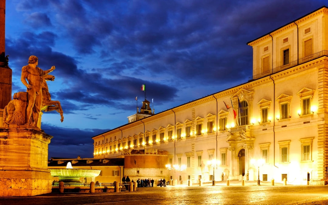 Oświetlony wieczorem Pałac Kwirynalski w Rzymie z monumentalnym posągiem Dioskura trzymającego konia na pierwszym planie