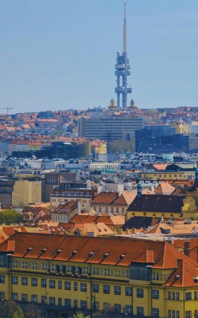 Panorama Pragi z charakterystyczną Wieżą Telewizyjną Žižkov górującą nad czerwonymi dachami miasta