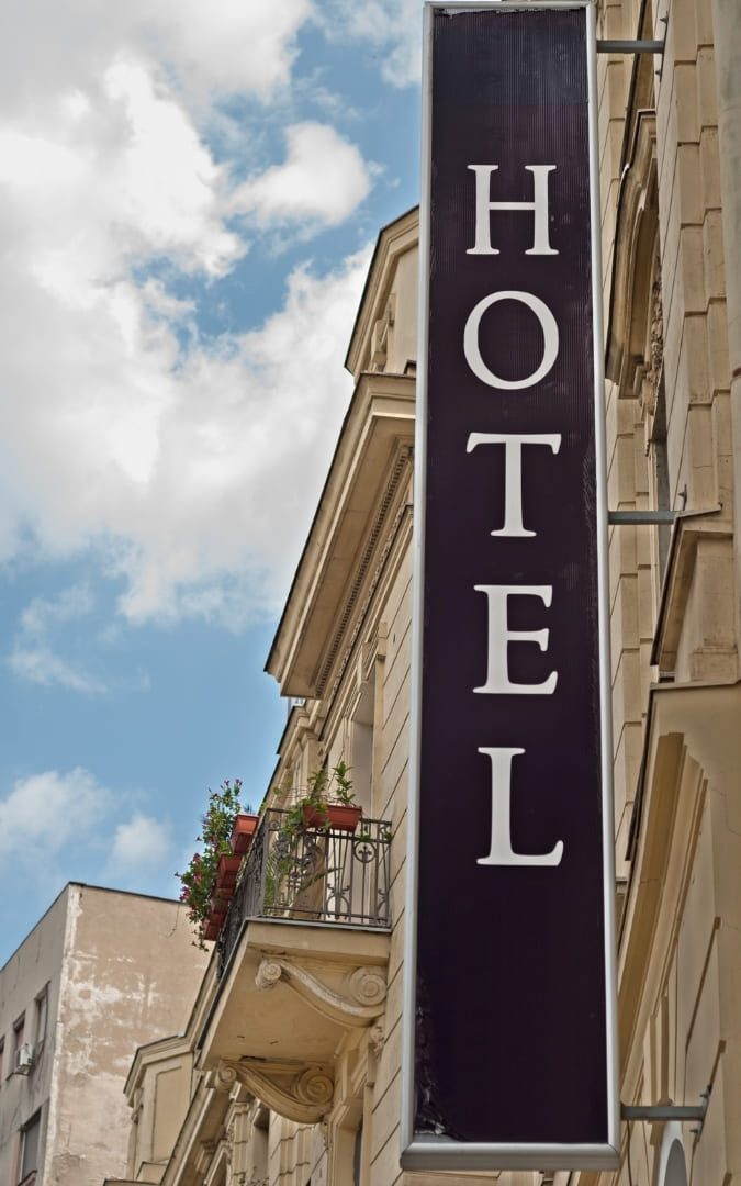 Pionowy czarny szyld z napisem HOTEL na fasadzie zabytkowej kamienicy