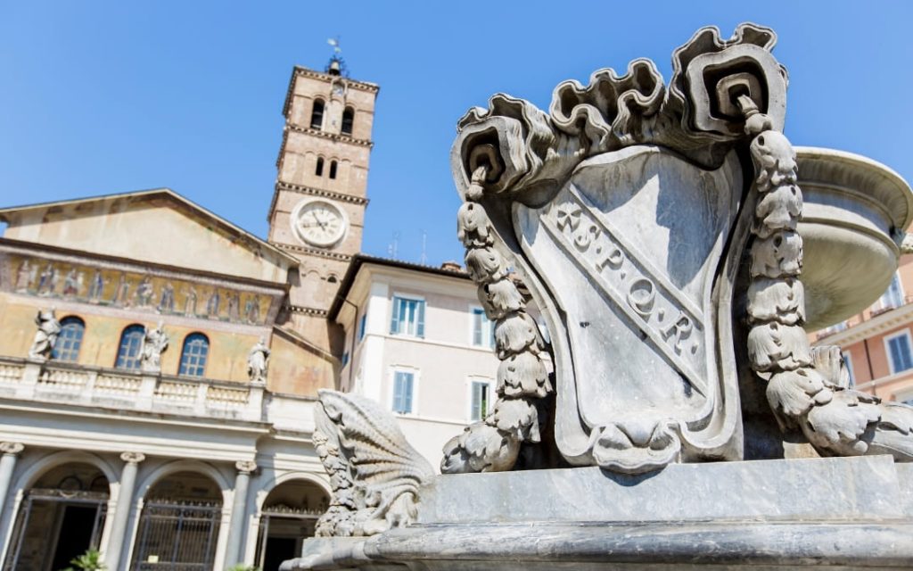 Plac Piazza di Santa Maria in Trastevere w Rzymie z zabytkową fontanną i fasadą Bazyliki Najświętszej Maryi Panny na Zatybrzu