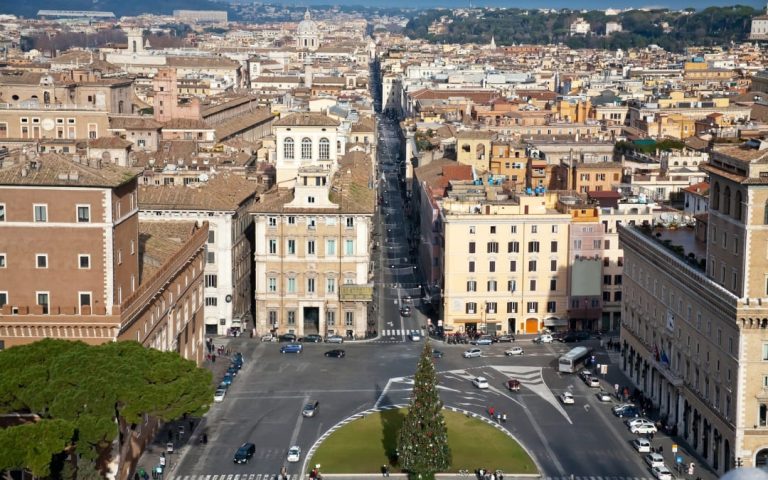 Plac Wenecki w Rzymie z ruchem samochodowym i początkiem ulicy Via del Corso