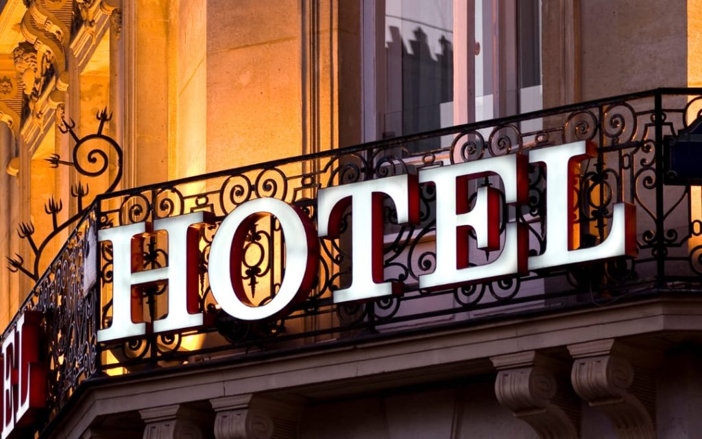 Podświetlony biały napis Hotel na kutej balkonowej balustradzie o zmierzchu