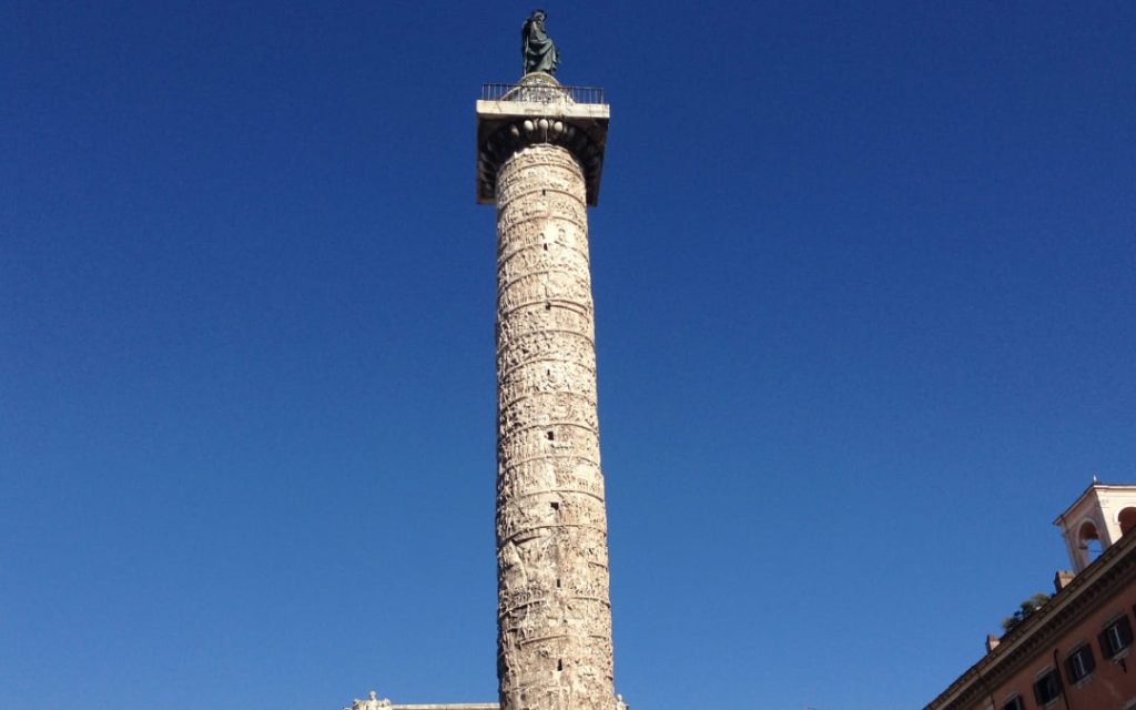 Starożytna rzymska Kolumna Marka Aureliusza z ozdobnym spiralnym reliefem na tle błękitnego nieba