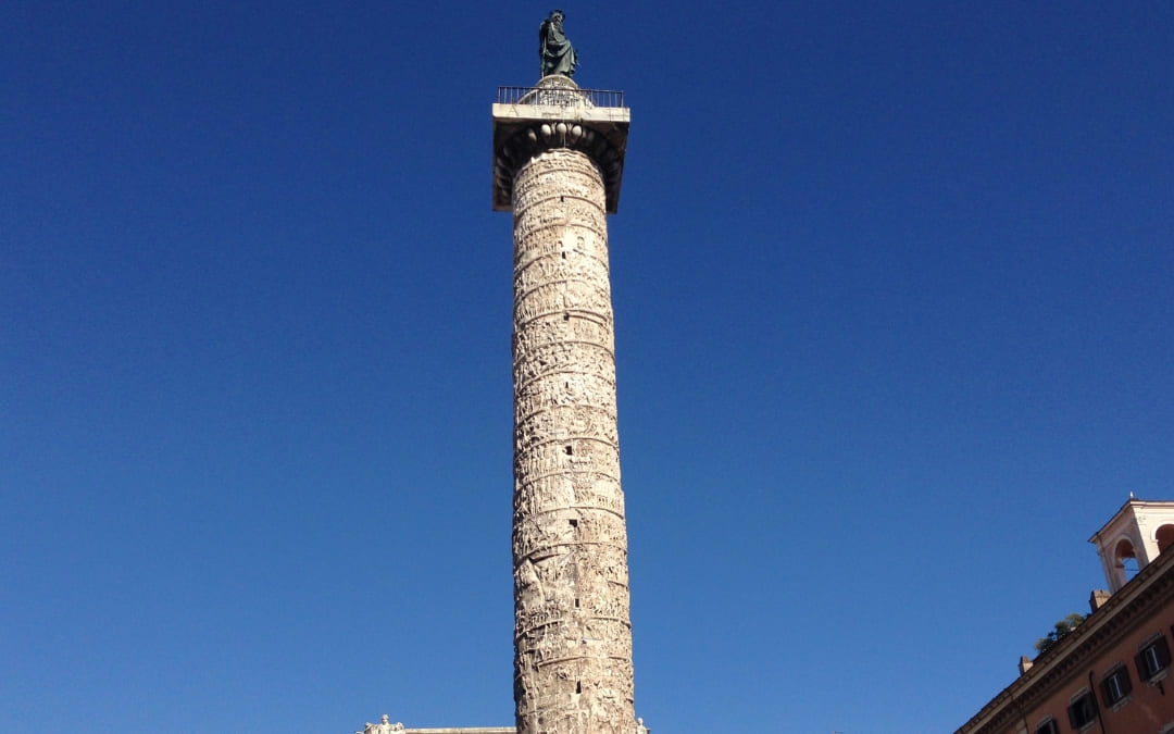 Starożytna rzymska Kolumna Marka Aureliusza z ozdobnym spiralnym reliefem na tle błękitnego nieba