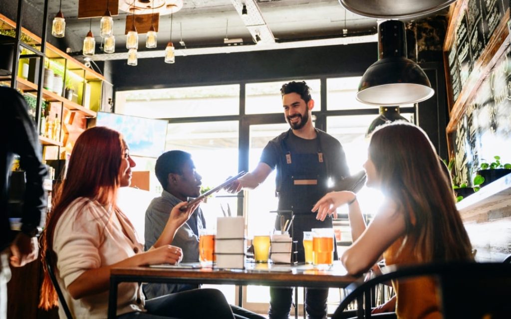Uśmiechnięty kelner podający menu gościom w nowoczesnej restauracji w Rzymie