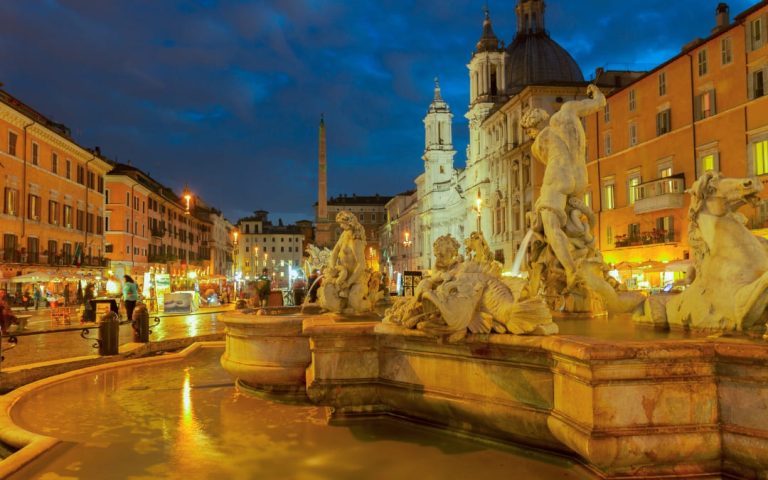 Widok na Piazza Navona w Rzymie o zmierzchu z podświetloną barokową fontanną i kościołem Sant'Agnese in Agone w tle