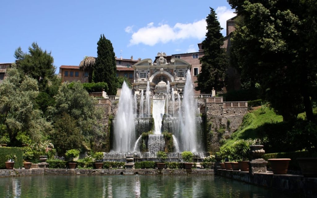 Wielopoziomowa fontanna i baseny z roślinnością w Villa d'Este w Tivoli pod błękitnym niebem