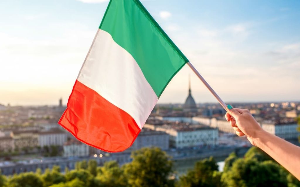 Włoska flaga trzymana w dłoni na tle panoramy 