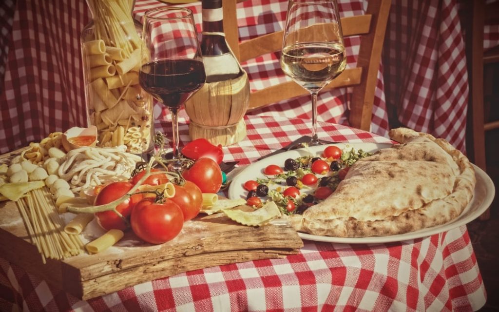 Włoska uczta na rzymskiej uliczce z pizzą calzone winem i świeżymi składnikami