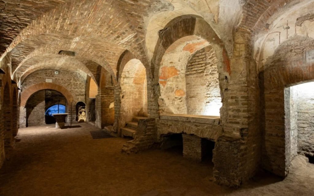 Wnętrze Katakumb Pryscylli w Rzymie z ceglanymi łukami i niszami grzebalnymi typu loculi