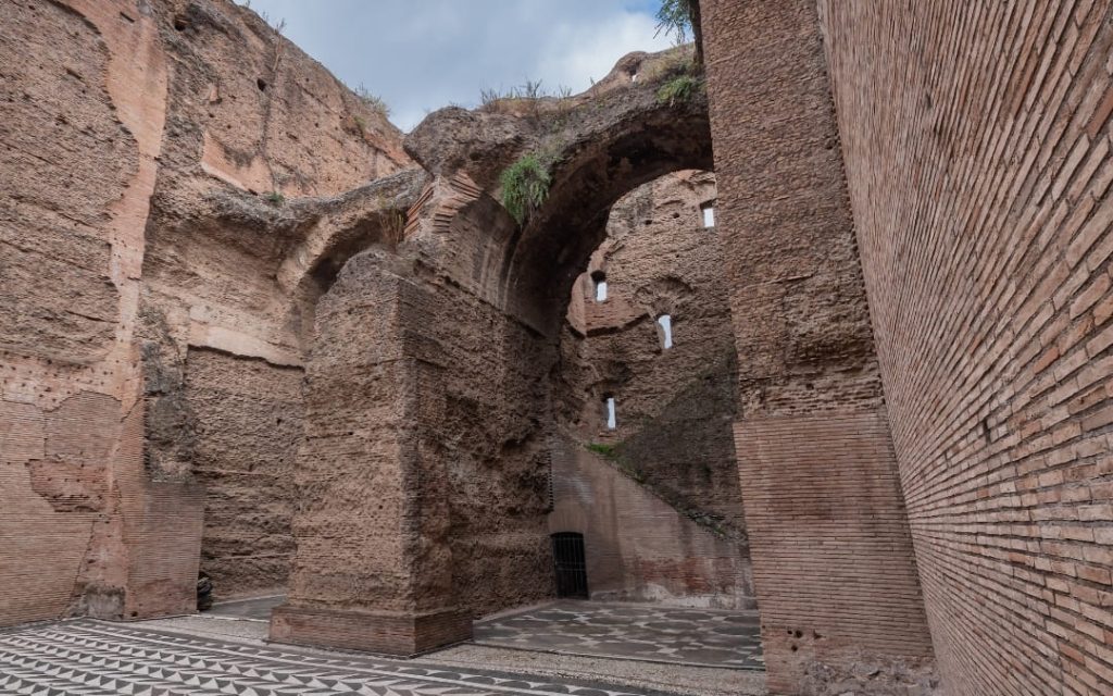 Wysokie, ceglane mury Term Karakalli z zachowanymi czarno-białymi mozaikami geometrycznymi na podłodze