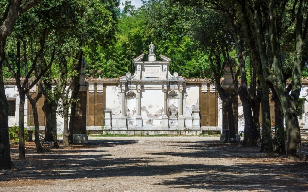 Zabytkowa, barokowa fasada Prospettiva del Teatro w ogrodach Villa Borghese w Rzymie, otoczona aleją wysokich drzew